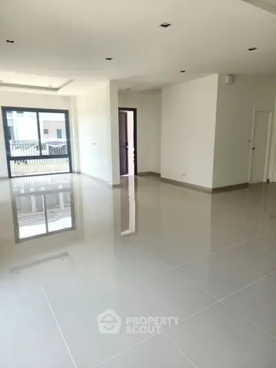 Spacious modern living room with glossy tiled floors and large windows for natural light.