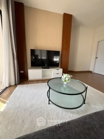 Modern living room with sleek TV stand and glass coffee table on plush carpet.