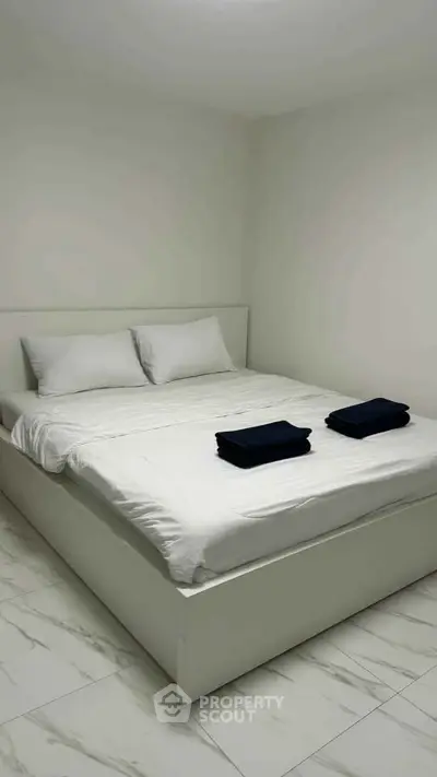 Minimalist bedroom with white bed and tiled floor, perfect for a serene living space.