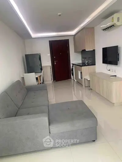 Modern living room with sleek furniture and integrated kitchen appliances in a stylish apartment.