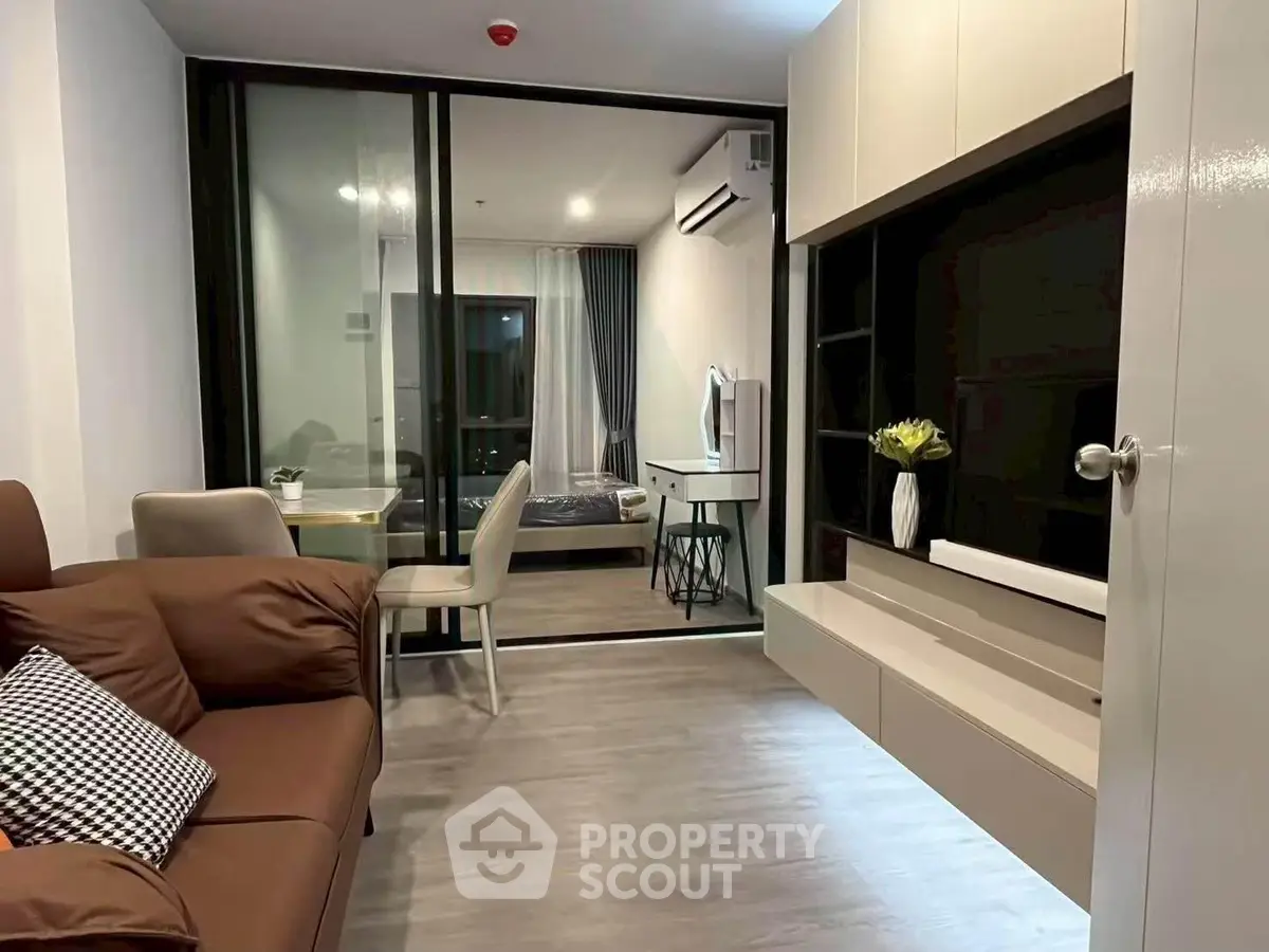 Modern apartment interior with stylish living room and bedroom separated by glass partition.