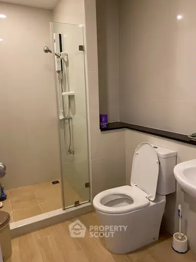 Modern bathroom with glass shower and sleek fixtures in contemporary apartment.