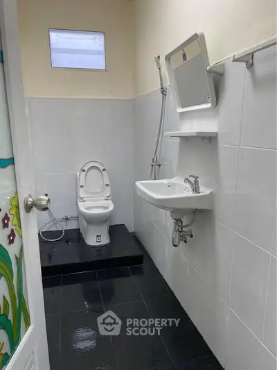 Compact bathroom with modern fixtures and elevated toilet platform.
