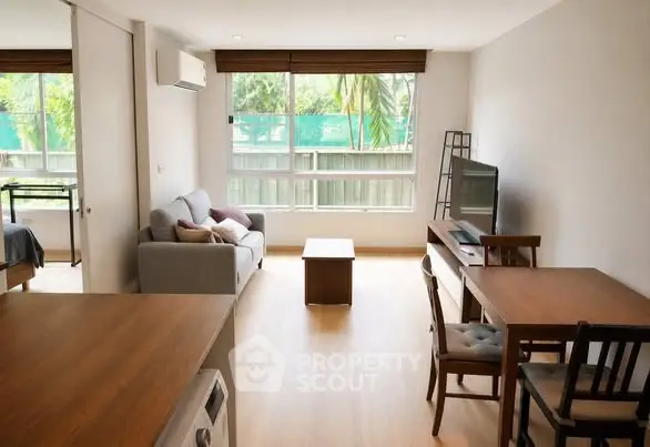 Modern living room with natural light, wooden flooring, and cozy furniture in a stylish apartment.