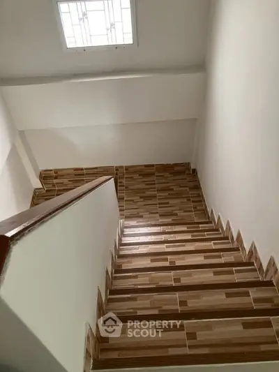Modern staircase with wooden steps and natural light from skylight