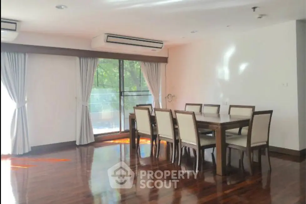 Spacious dining area with elegant wooden flooring and large windows for natural light.