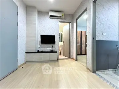 Modern apartment interior with sleek design and open layout, featuring a wall-mounted TV and stylish flooring.