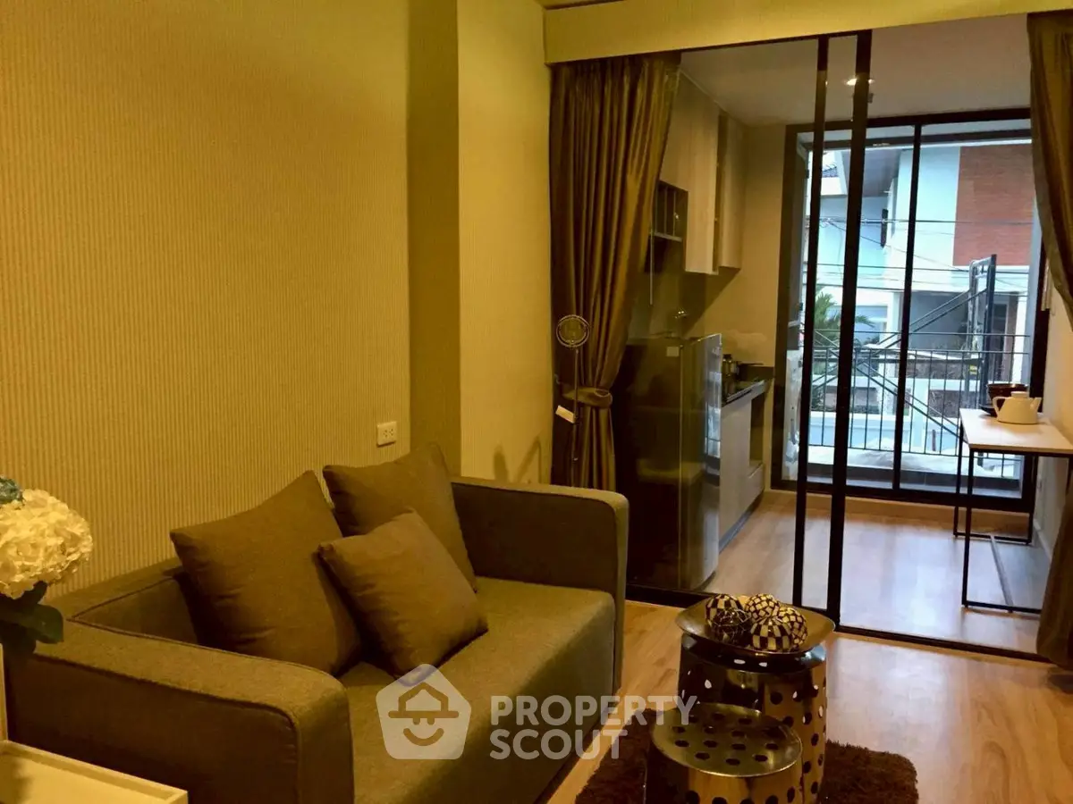 Modern living room with cozy sofa and open kitchen layout, featuring a balcony view.