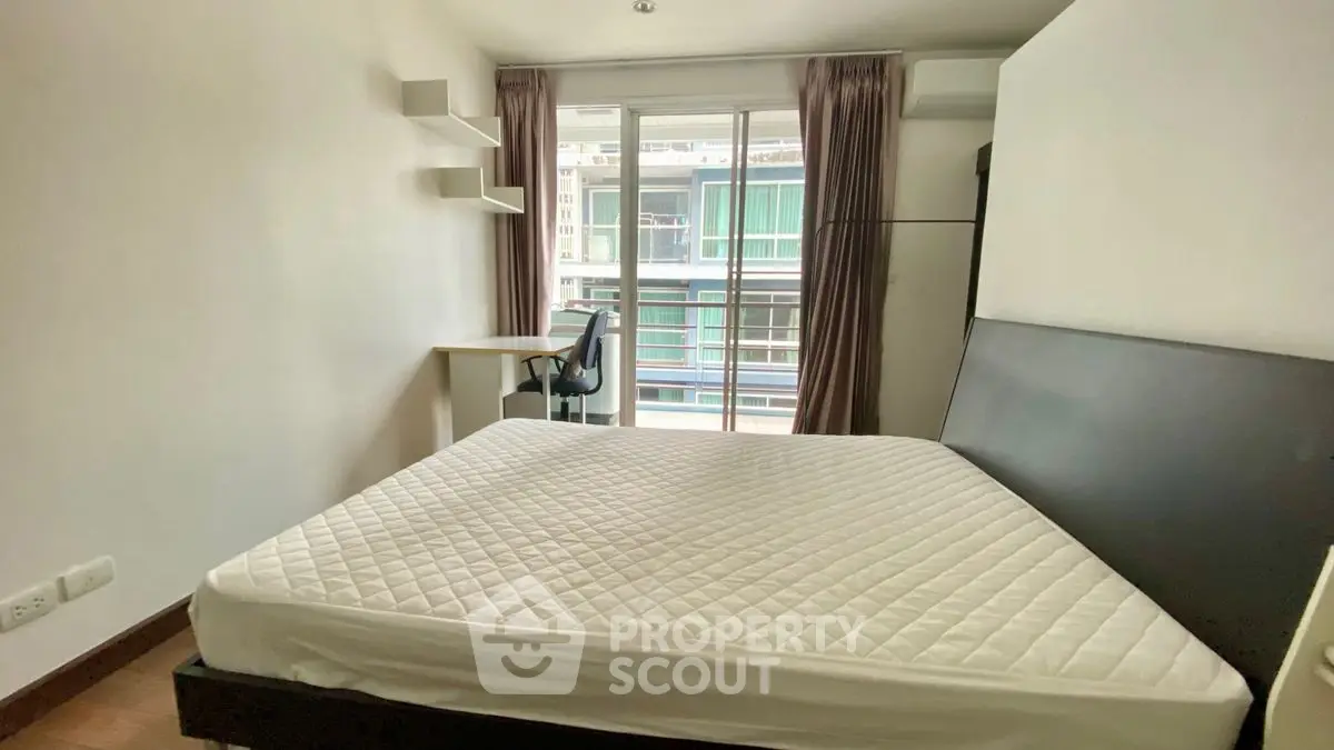 Cozy bedroom with balcony view, featuring a comfortable bed and study desk.