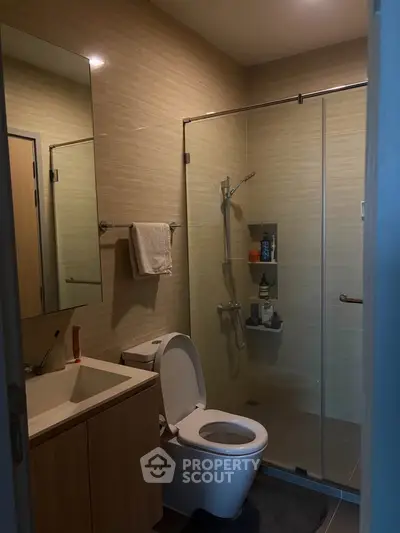 Modern bathroom with glass shower and sleek vanity in contemporary apartment.