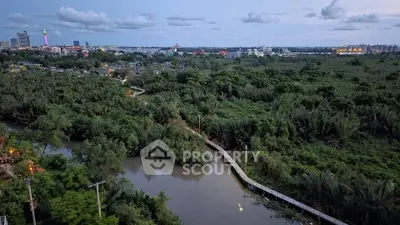Scenic aerial view of lush greenery and winding river near urban skyline at dusk.