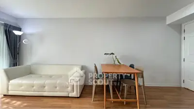 Modern living room with white sofa and dining table, featuring minimalist decor and wooden flooring.
