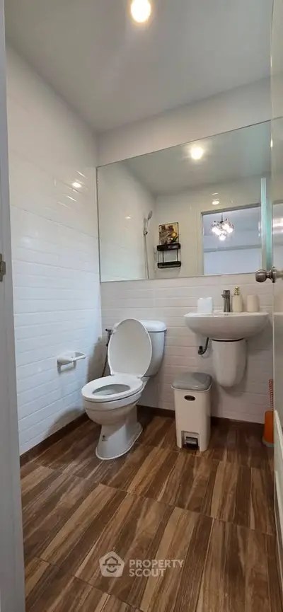 Modern bathroom with sleek fixtures and wood-style flooring in a contemporary home.