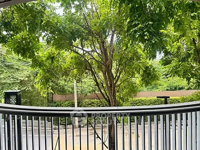 Charming balcony view with lush greenery and street scenery, perfect for relaxation and enjoying nature.