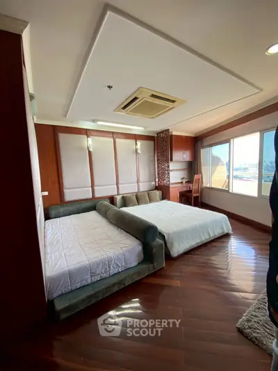 Spacious bedroom with large windows and elegant wooden flooring