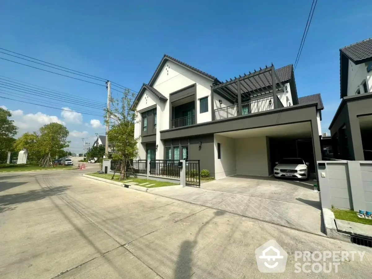 Modern two-story house with carport and landscaped front yard in sunny neighborhood.