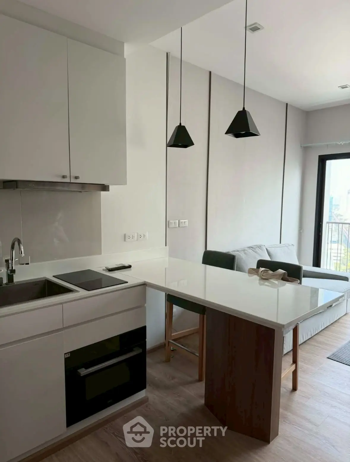 Modern kitchen with sleek design and open layout, featuring a cozy living area and balcony view.
