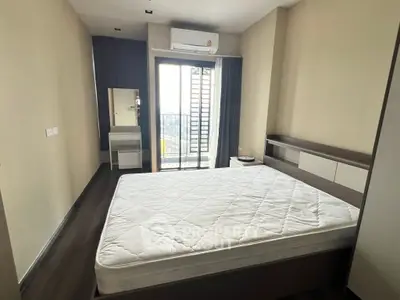 Modern bedroom with balcony access and sleek furnishings in a high-rise apartment.