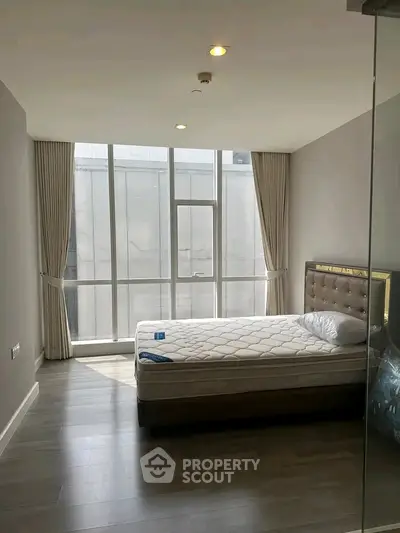 Spacious bedroom with large windows and modern decor in a luxury apartment.