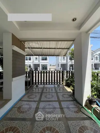 Charming covered patio with tiled floor and garden view in modern residential area.