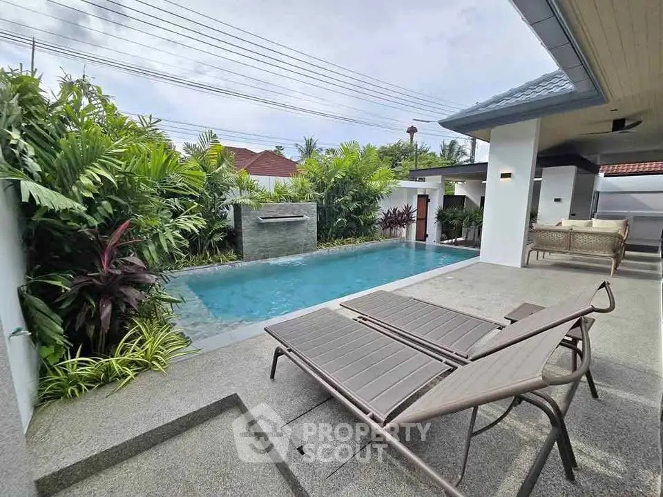 Luxurious private pool area with lush greenery and modern patio furniture.