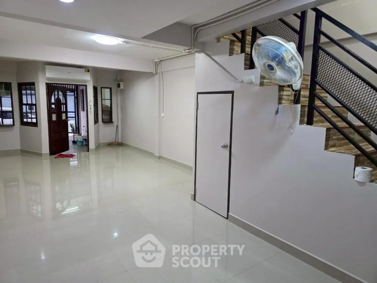 Spacious modern living area with sleek staircase and glossy tiled floors.