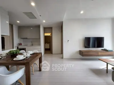 Modern open-plan living room with sleek furniture and wall-mounted TV