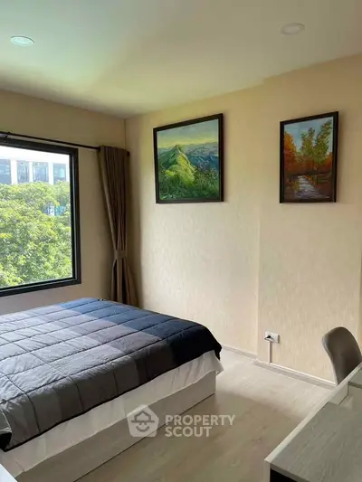 Bright bedroom with large window and scenic paintings, offering a serene view and modern furnishings.