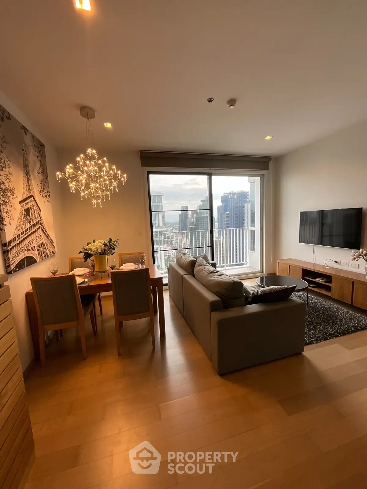 Modern living room with city view, stylish decor, and elegant chandelier lighting.