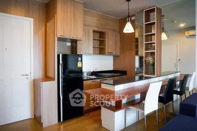 Modern kitchen with sleek wooden cabinets and dining area in open layout apartment.