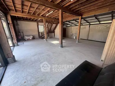 Spacious open-plan interior with wooden beams and concrete floor, ideal for customization.