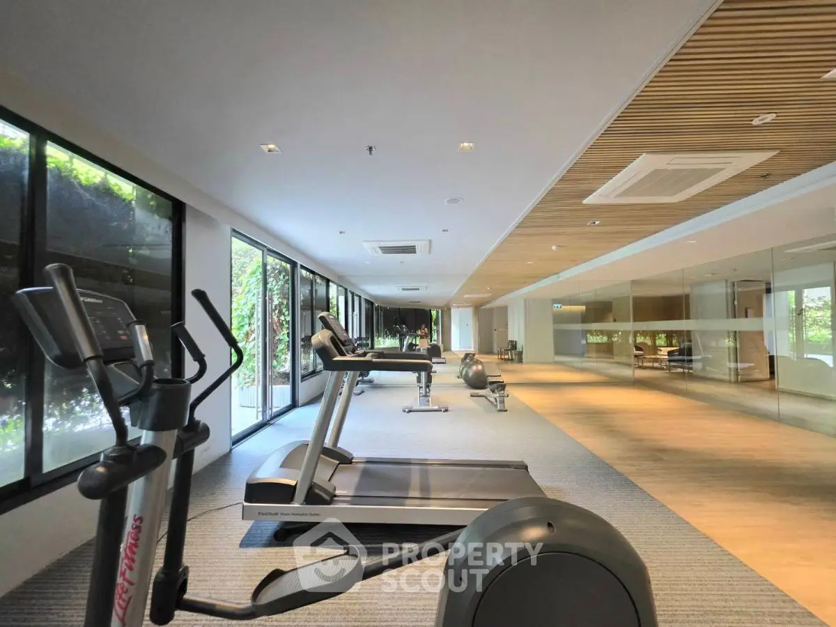 Spacious modern gym with state-of-the-art equipment and large windows for natural light.