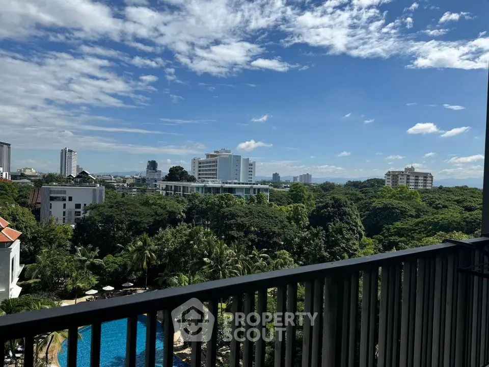 Stunning balcony view overlooking lush greenery and cityscape with a pool in the foreground.
