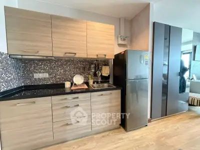 Modern kitchen with sleek cabinets and stainless steel fridge in stylish apartment.