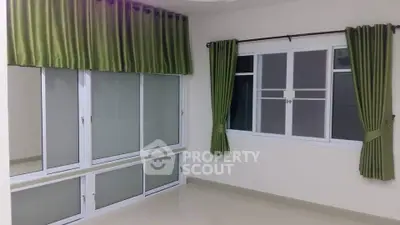 Spacious corner unit with large windows and elegant green curtains, perfect for natural light lovers.