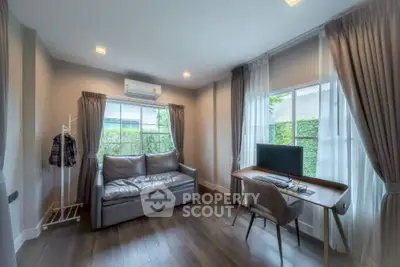 Modern study room with natural light, featuring a sleek desk and comfortable seating.