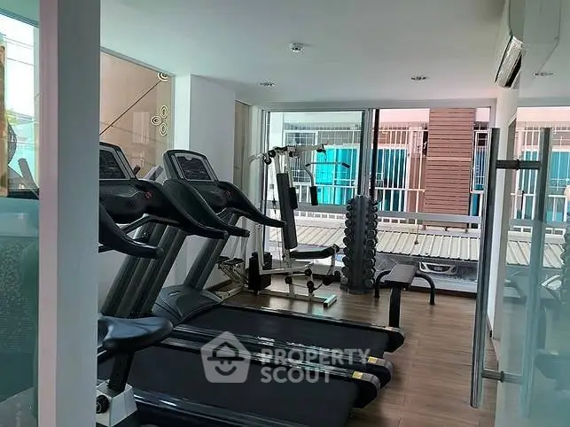 Modern gym with treadmills and weights in a bright, spacious room.