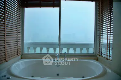 Luxurious bathroom with large bathtub and stunning city view through wide windows.