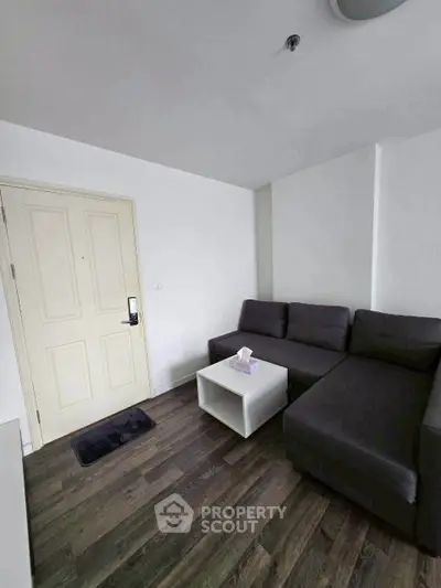 Cozy living room with modern gray sofa and wooden flooring, perfect for relaxation.