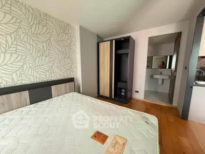 Modern bedroom with stylish wallpaper and wooden flooring, featuring a bed and wardrobe.