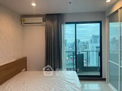 Modern bedroom with city view and balcony access in high-rise apartment.
