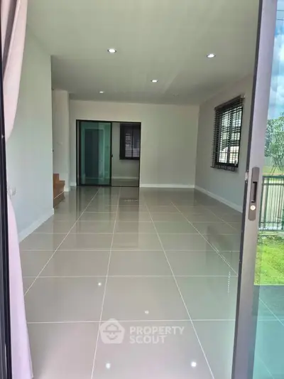 Spacious modern living room with large windows and glossy tiled floors, perfect for natural light and open living.