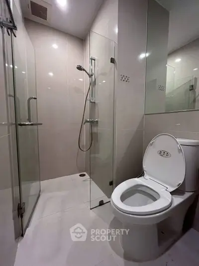 Modern bathroom with glass shower and sleek toilet in contemporary apartment.