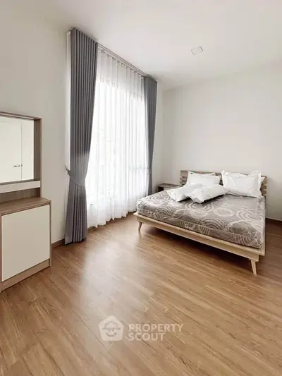 Spacious minimalist bedroom with large window and elegant curtains