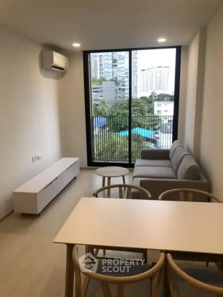Modern living room with large window and city view, featuring sleek furniture and natural light.