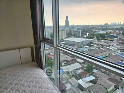 High-rise bedroom with panoramic city view through large windows.
