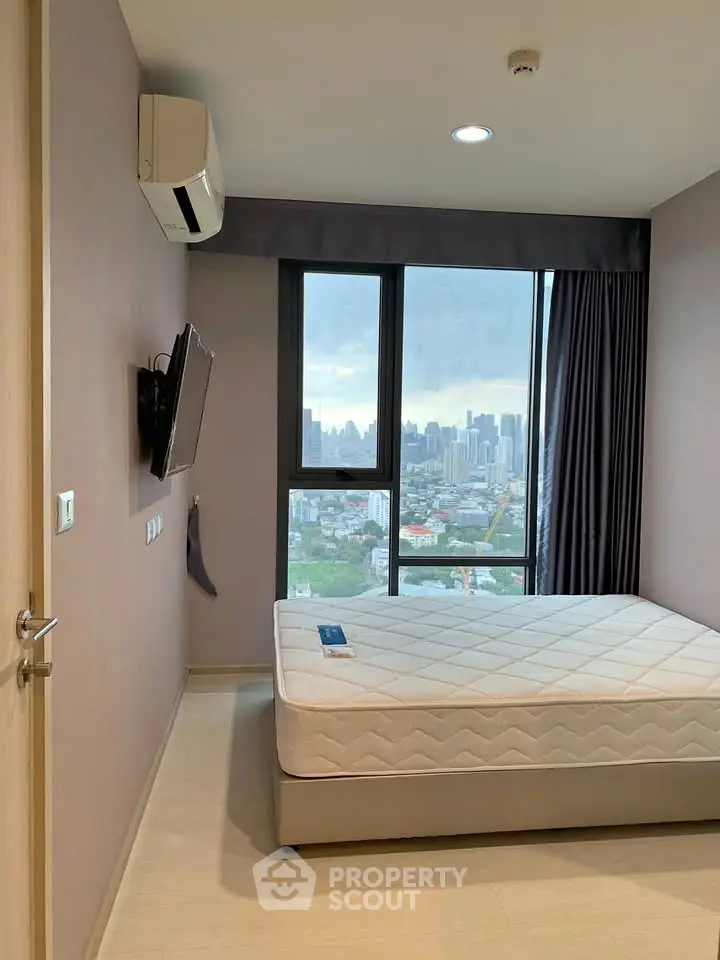 Modern bedroom with city view, featuring a wall-mounted TV and air conditioning.