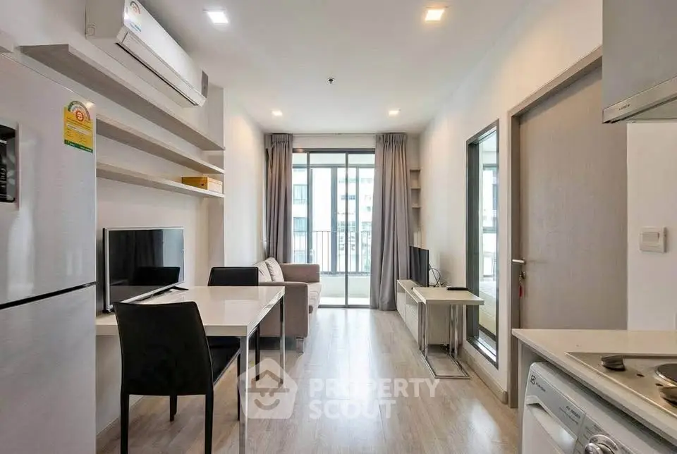 Modern apartment interior with open layout, featuring sleek kitchen and cozy living area with balcony access.