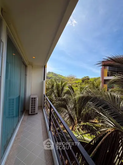 Charming balcony with lush tropical views in modern apartment complex.