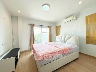 Spacious bedroom with large window and modern furnishings in a bright, airy apartment.